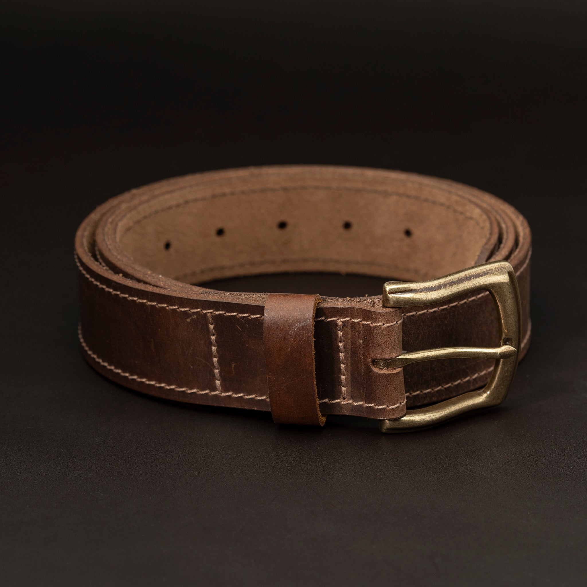 Dark brown leather belt with brass buckle and light stitching